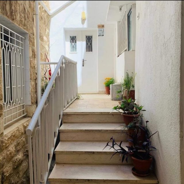 Der Eingang zu Wohnung geht über eine Treppe. Gerade aus befindet sich eine Tür und rechts ist die Haustür. Vor der Tür stehen jede Menge Pflanzen