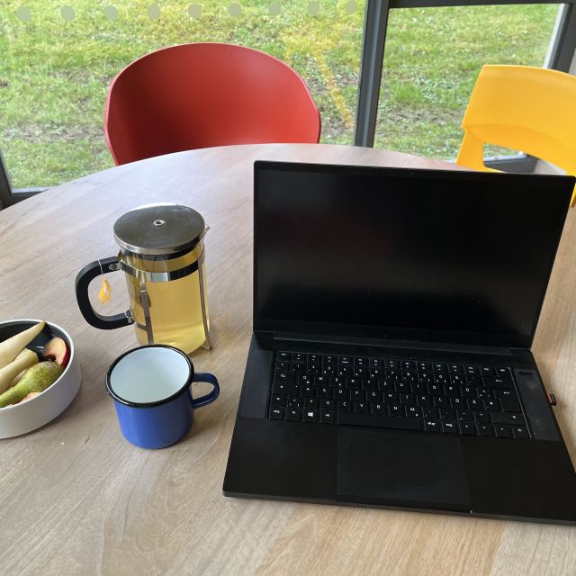 Laptop auf Schreibtisch mit Snacks und Tee daneben