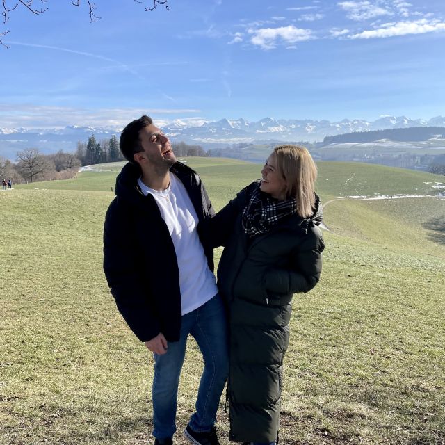 Tobias und eine Freundin lachen aus vollem Herzen auf dem Gurten und hinter ihnen sieht man in der Ferne die Alpen.