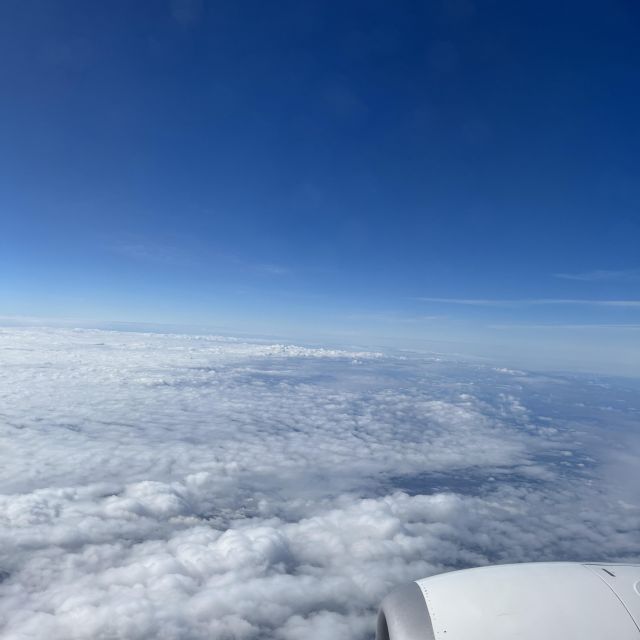 Blick aus dem Flugzeugfenster auf blauen Himmel, weiße Wolken und eine Drüse des Flugzeugs.