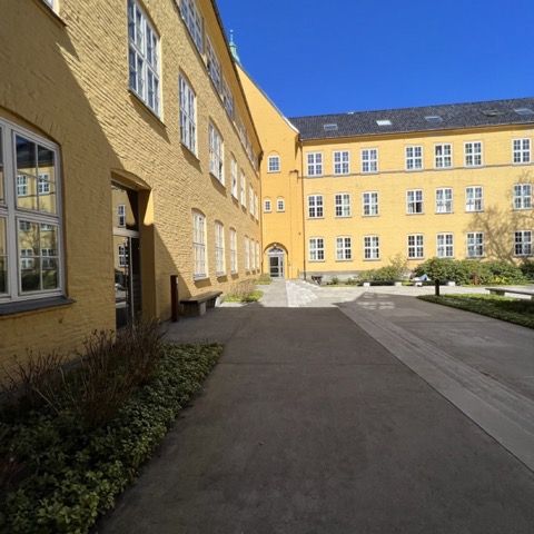Fakultät mit Innenhof, Sonne und gelbgestrichenem Gebäude