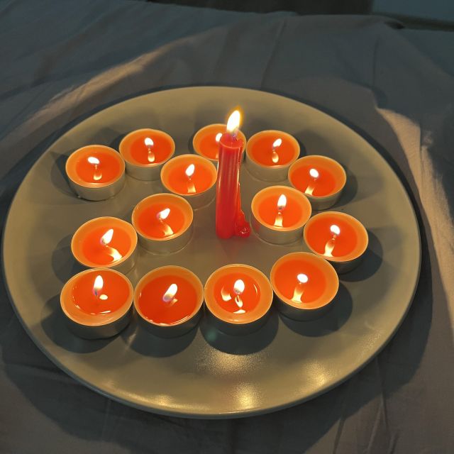 Ein Teller voller brennender Teelichter, die eine 23 darstellen