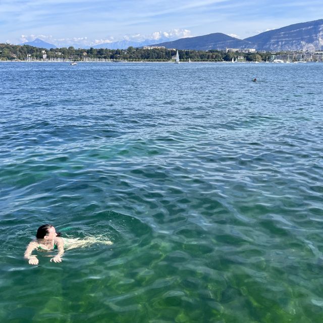 Frau schwimmt in See, im Hintergrund Ufer und Berge