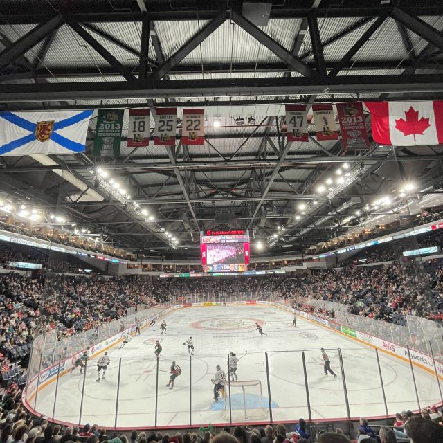 Bild auf eine Eishalle, in der ein Eishockey-Spiel stattfindet. Die Halle ist voll besetzt. Die Flagge Kanadas und die Flagge Nova Scotias hängen von der Decke herab.