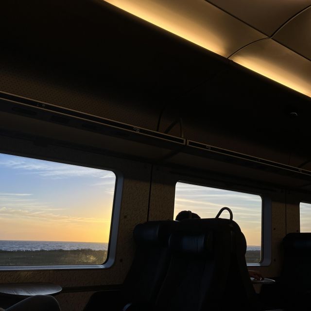 Das Bild ist aus dem Zugfenster ausgenommen und zeigt den Sonnenuntergang über dem Meer.