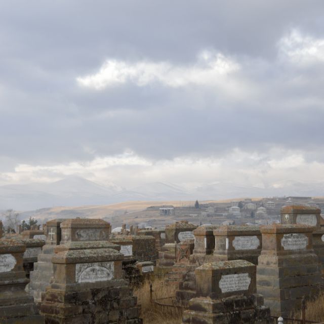 Weitere Grabsteine im Friedhof, dazwischen wächst hohes Graß.